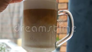 咖啡拿铁与勺子混合。 将咖啡与牛奶混合，近距离观看